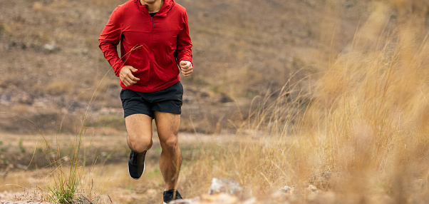 Trail runner man running on rocky mountain. Athlete jog exercising outdoor for healthy. Confident and powerful marathon man running workout and cardio. Sport and Lifestyle concept.