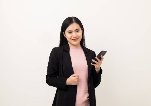istock Cheerful young Asian woman using smartphone and checking message on mobile chat application isolated white background. Fashion style asian lovely woman playing game or shopping online by cellphone 1387605636