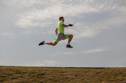 Strong sportsman is jumping while running on his trail for that great form