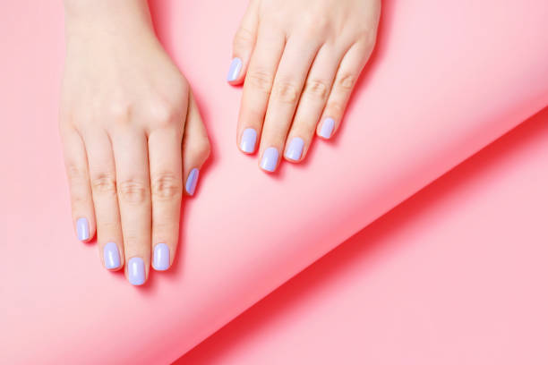 istock Female hands with manicure on pink background, top view 1387609849