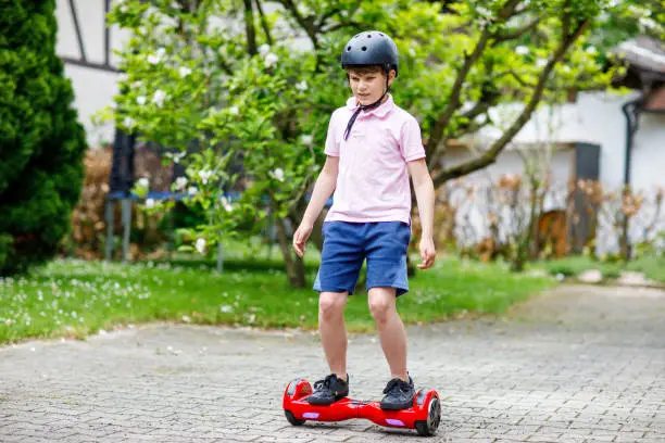 Active kid boy on hover board. Child driving modern balance hoverboard. Excercise and sports for children, outdoor activity for young kids