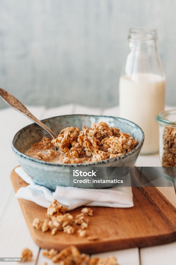 Granola in a bowl and a milk bottle Nut granola in a bowl standing on a cutting board Granola Stock Photo