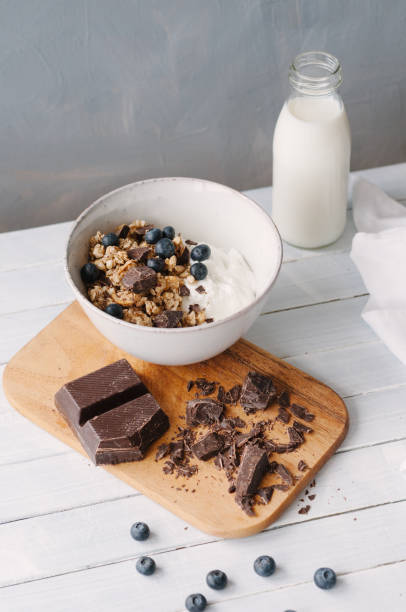 Granola with blueberries and chocolate in a bowl standing on a wooden table