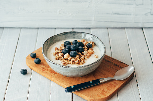 Granola with blueberries and hazelnuts in a bowl standing on a cutting board
