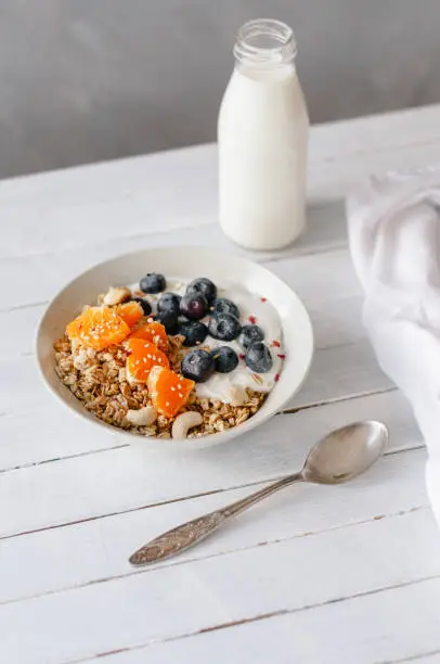 Granola with blueberries and tangerine in a bowl standing on a table