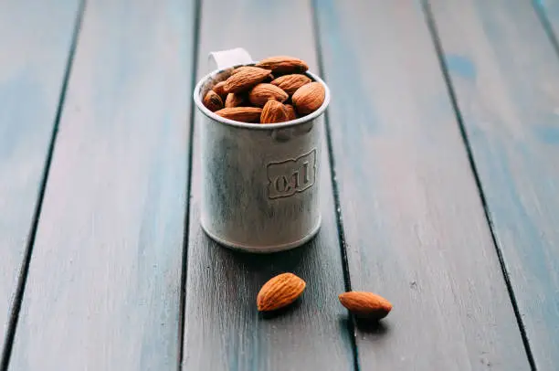 Metal measuring cup filled with almonds standing on a table