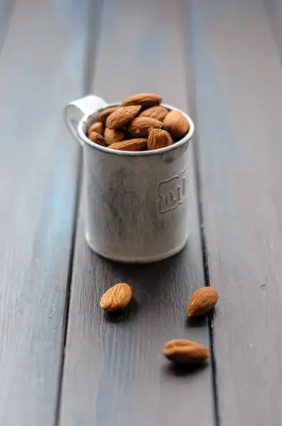 Metal measuring cup filled with almonds standing on a table