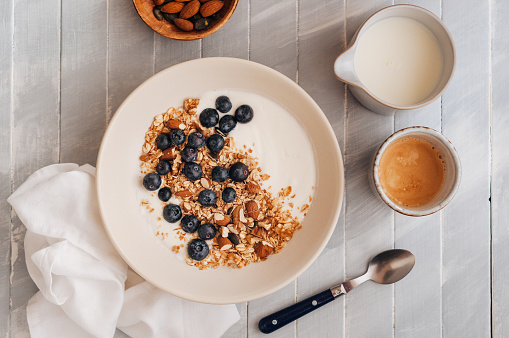Oatmeal with yogurt, almonds and blueberries on a wooden table