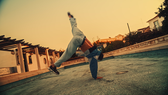 Activel Young Latin Man in Stylish Clothes Actively Breakdancing, Spinning on Hands on the Street of an Old Town in a City. Scene Shot in an Urban Environment in Ancient Cultural Tourist Location.