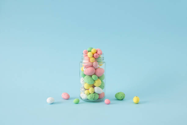 istock Pastel colored pink, yellow, green and white Easter quail eggs in a glass jar. Creative concept on blue background.