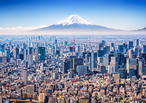 Aerial view of Mount Fuji, Tokyo Tower and modern skyscrapers in Tokyo on a sunny day.