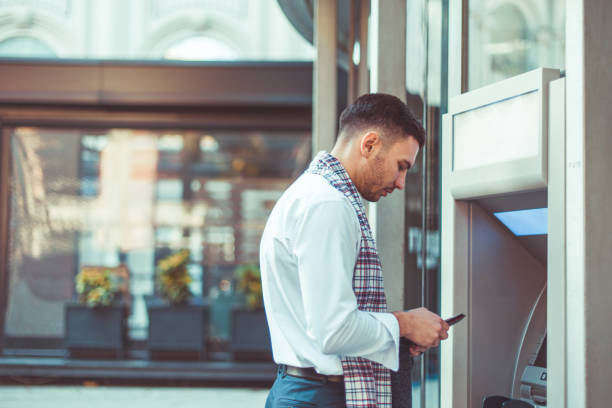 istock Handsome businessman standing next to ATM 1387618437