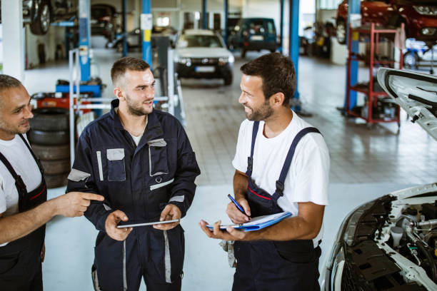 istock Happy auto mechanics talking while working in repair shop. 1387618449