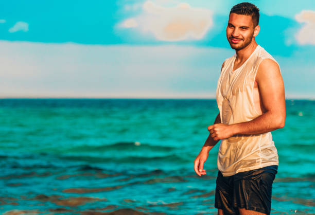 istock Happy handsome smiling male model on the beach 1387619355