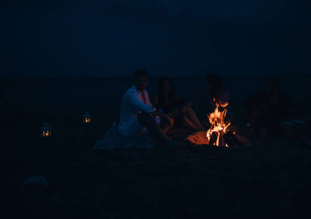 istock Friends were sitting around the fire while drinking beer and playing guitar 1387619356