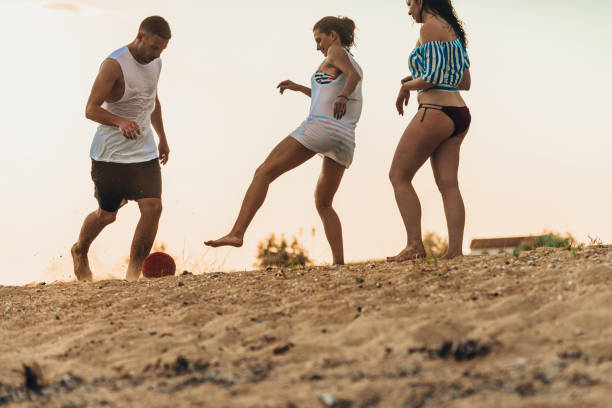 istock Multicultural friends playing soccer together on the sandy beach 1387619384