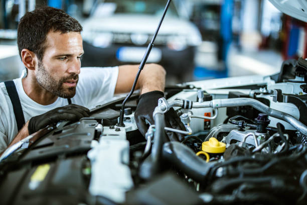 istock Young mechanic examining engine problems in auto repair shop. 1387619688