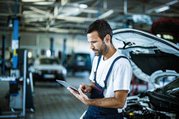 auto repairman working on digital tablet in a workshop. - mechanic auto repair shop auto mechanic repairing imagens e fotografias de stock