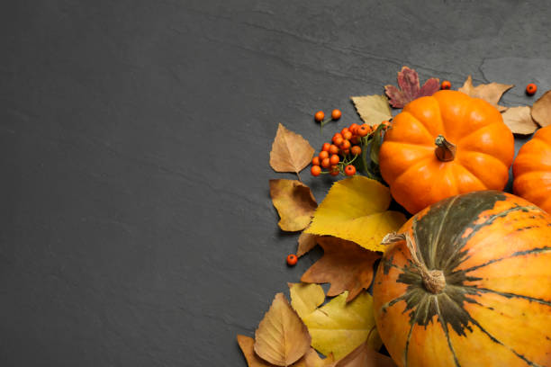 istock Flat lay composition with pumpkins and autumn leaves on black slate table. Space for text 1387620921