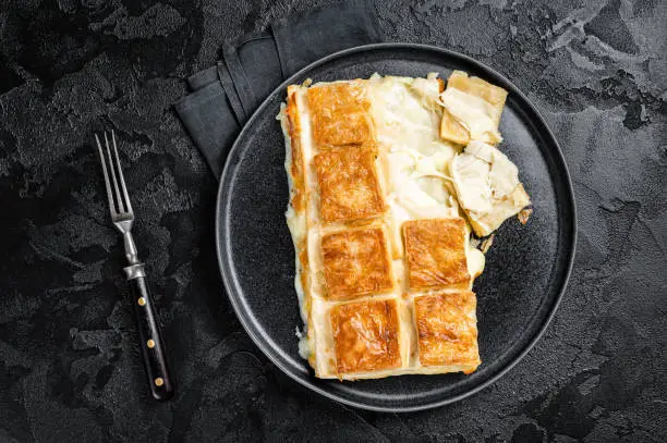 Turkish Su Boregi pie, Tabla borek or burek in plate. Black background. Top view.