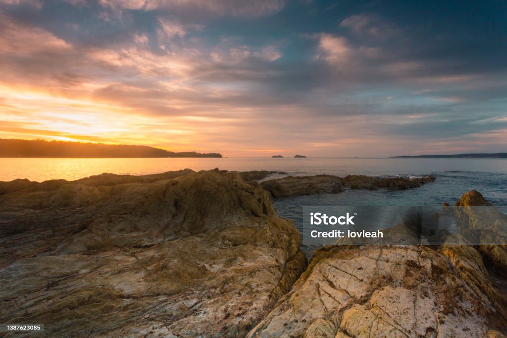 Golden sunrise over the coastal bay Golden sunrise burst over the tranquil bay.  Sandstone rock weathered by the elements in the foreground Australia Stock Photo