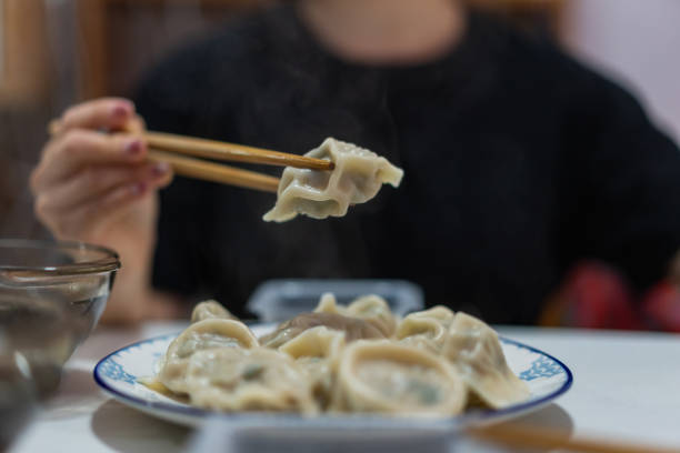 Woman holding a dumpling with chopsticks close-up