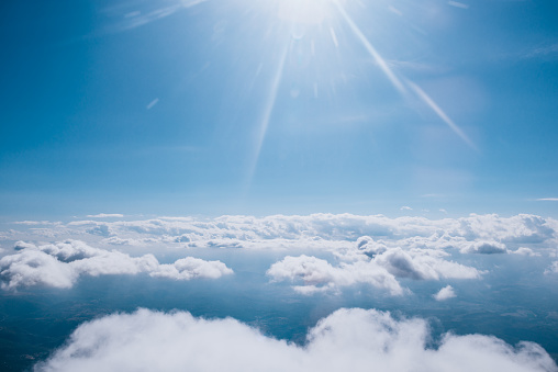 White clouds and sunny sky as seen through a window of an airplane