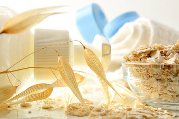 Detail of bath products with oat extract on white table with straws. Front view. Horizontal composition.