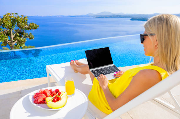 istock Woman working on laptop computer outdoors by the pool 1387626601