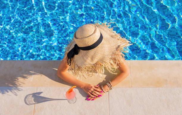 istock Woman drinking cocktail by the pool, view from above 1387626657