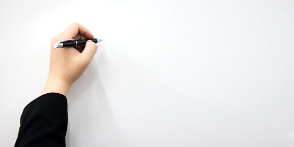 Man's hand holding a pen writing on a white background. with space to design for you