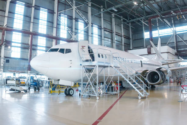 White passenger airplane in the hangar. Airliner under maintenance White passenger airplane in the hangar. Airliner under maintenance. Checking mechanical systems for flight operations airplane hangar stock pictures, royalty-free photos & images