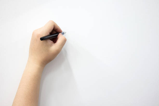 istock Man's hand holding a pen writing on a white background. 1387627248