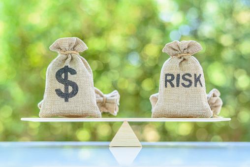 Risk assessment / risk analysis and management concept : Dollar and risk bags on a basic balance scale. The image depicting evaluation of financial risk that investor involved in stock, futures and derivatives market.