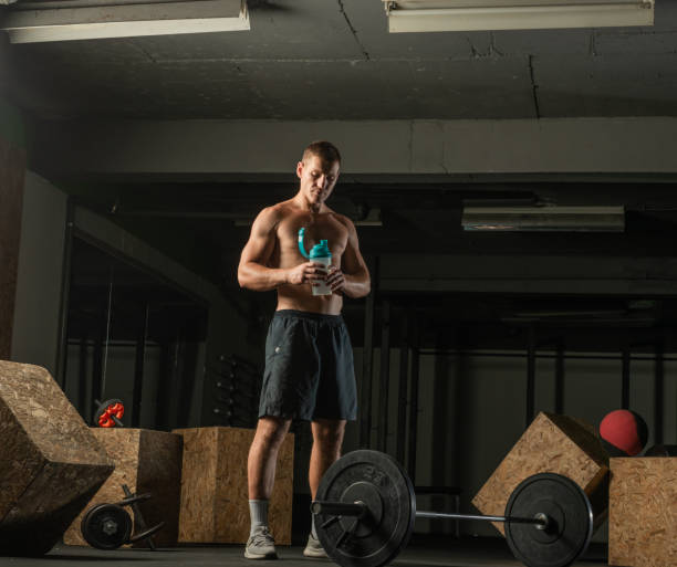 muskulöser mann, der eine pause von einem hardcore-training macht, während er wasser trinkt. - bicep human arm macho flexing muscles stock-fotos und bilder