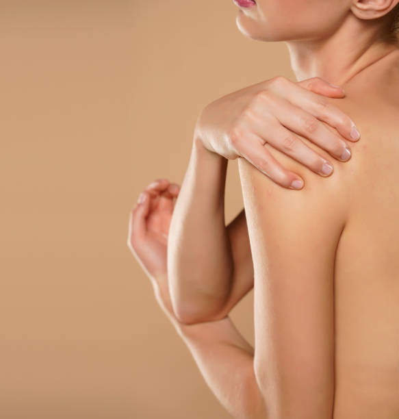 istock Woman with shoulder pain on a beige 1387628774