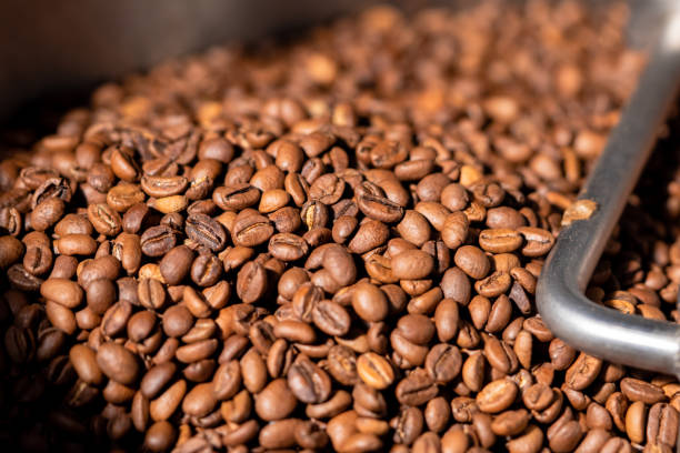 istock Production of freshly roasted coffee beans. Roasting process in an industrial coffee roasting machine in a factory. Mixing roasted coffee beans. Food and drink background for cafe 1387629241