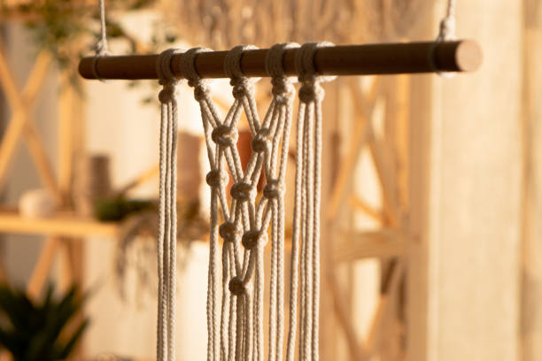 istock Pattern of whites macrame threads on a stick for decoration or home decor. Home decor idea handmade macrame cotton. Knotted lace, decorative ornament for decorating a cozy interior. Close up 1387629439