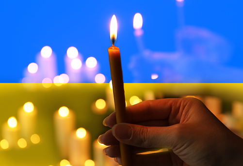 Woman with candle against Ukrainian national flag, closeup