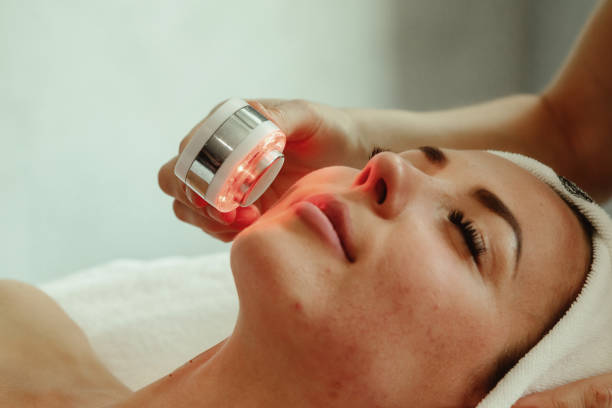 istock Beautician doing led light therapy to woman with problematic skin in SPA 1387630775