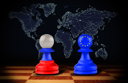Pawns with European union and Russian flags on chessboard against dark background with world map. Political feud