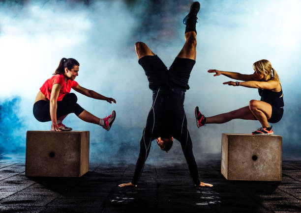 Group of athletic people jumping over some boxes in a cross-training gym