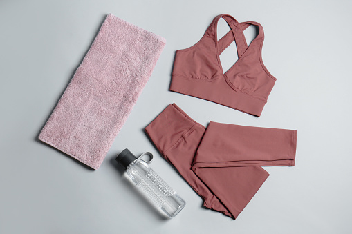 Sportswear, bottle of water and towel on grey background, flat lay. Yoga equipment