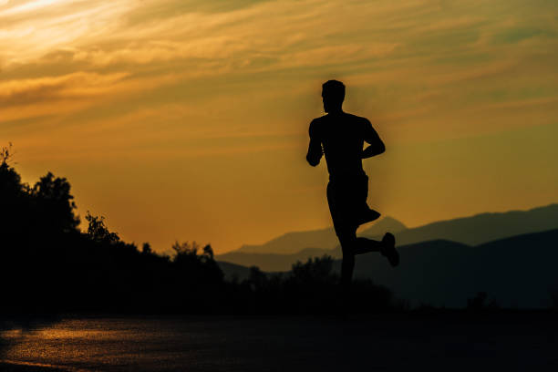 istock Young silhouette man exercise running outdoors keeping fit at mountain road on sunset 1387631192