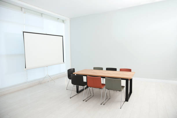 istock Conference room interior with wooden table and video projection screen 1387631871