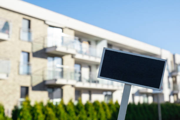 istock Blank Black billboard against new apartment building Empty mockup template Blackboard label Home for rent. Apartments for sale. Sign in front of new home. Advertisement 1387632223