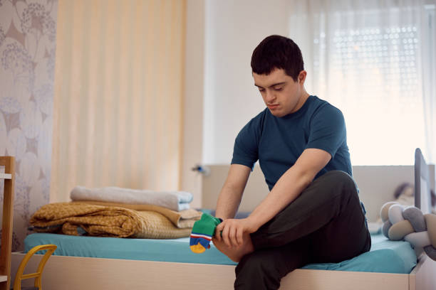 Man with down syndrome dressing up his socks at home.