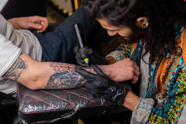 istock Man is tattooing a man's arm 1387633930