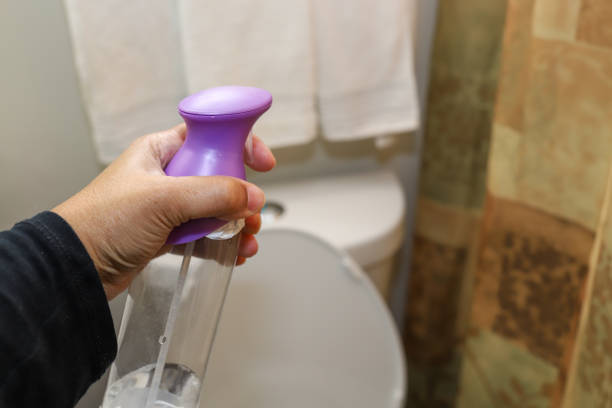 A black African-American woman holding a can of air freshener in her hand in a bathroom stock photo