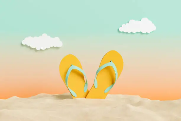 Photo of flip flops on beach sand with sunset studio background